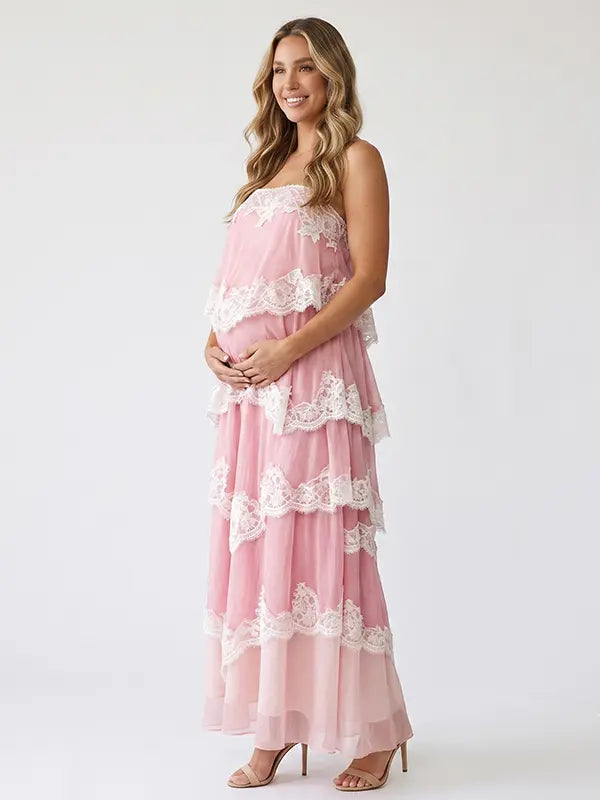 a pink tiered lace maternity maxi dress with layered chiffon, white lace trim, and an adjustable lace-up back for baby shower, maternity photoshoot, gender reveal, and bridal shower.