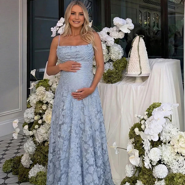 Pregnant woman wearing blue floral open back maternity maxi dress for baby shower photoshoot