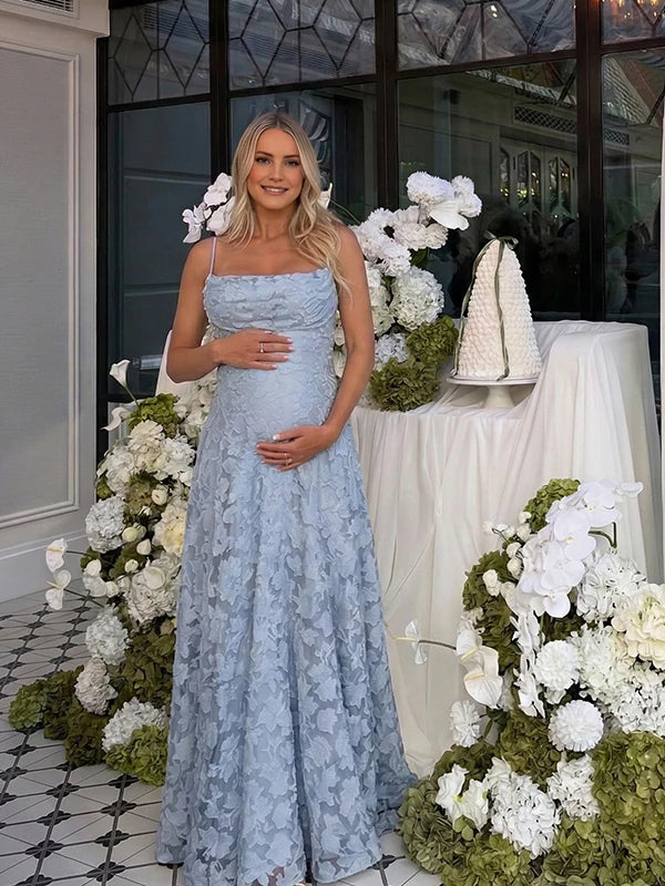 Pregnant woman wearing blue floral open back maternity maxi dress for baby shower photoshoot