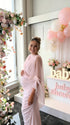 Side view of blush pink one shoulder maternity dress showing baby bump