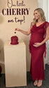 burgundy mesh maternity gown with draped neckline and cascading ruffle details