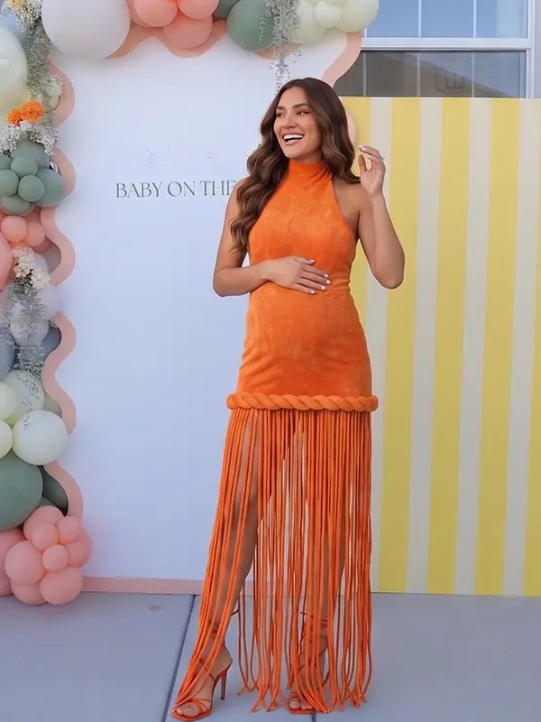 Burnt orange fringe halter maternity maxi dress with tassel hem, bodycon pregnancy gown for fall baby showers, pumpkin patch maternity photoshoots, harvest celebrations, and autumn pregnancy portraits.