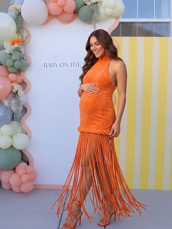 Burnt orange fringe halter maternity maxi dress with tassel hem, bodycon pregnancy gown for fall baby showers, pumpkin patch maternity photoshoots, harvest celebrations, and autumn pregnancy portraits.