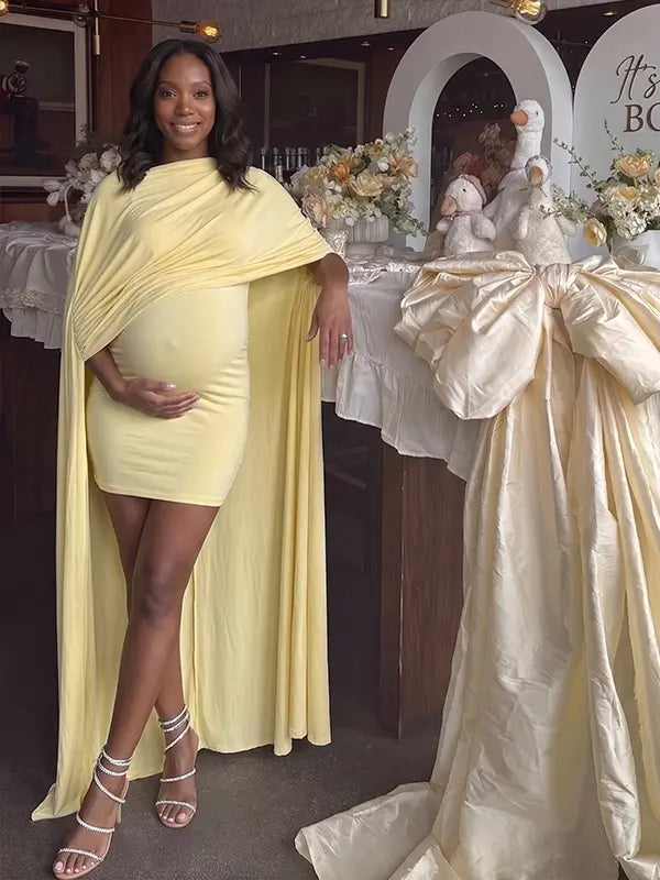butter yellow maternity cape dress with bodycon mini silhouette and dramatic flowing drape