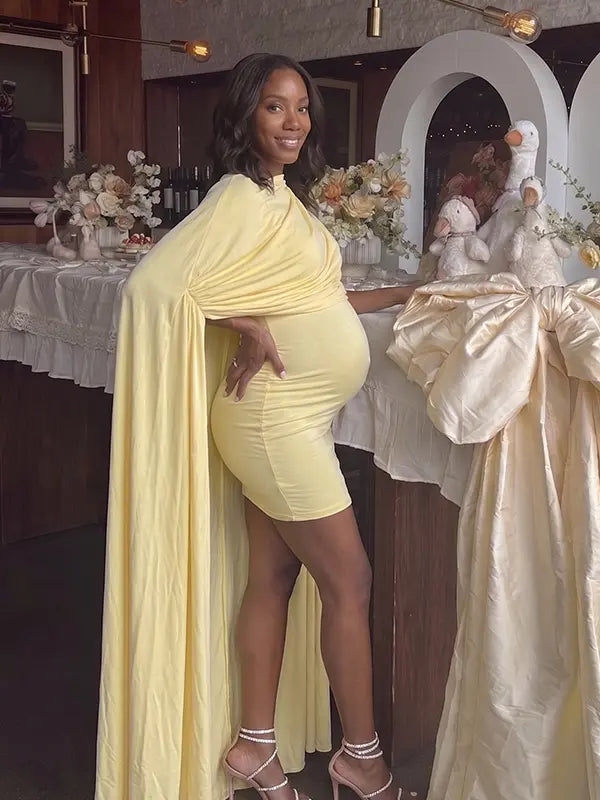 butter yellow maternity cape dress with bodycon mini silhouette and dramatic flowing drape