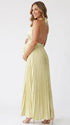 Pregnant model wearing a butter yellow pleated satin halter maternity maxi dress with deep V neckline and flowing skirt for summer baby shower, garden party and maternity photoshoot.