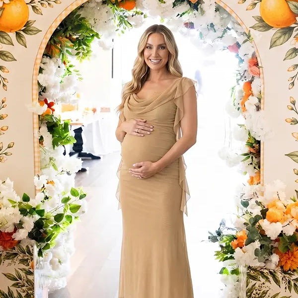 champagne beige maternity gown with draped neckline and cascading mesh ruffle details