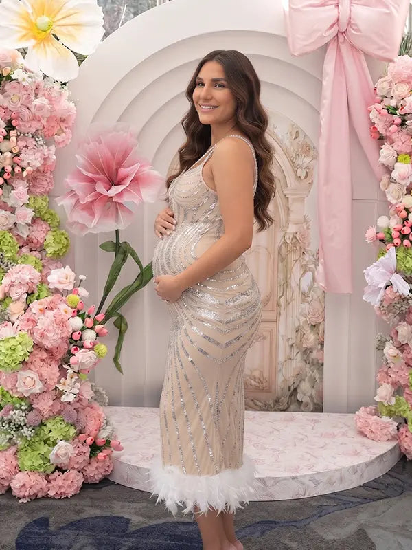 A champagne sequin feather trim maternity midi dress with illusion mesh, perfect for luxury maternity photoshoots, Gatsby baby showers, pregnancy announcements, and elegant formal celebrations.