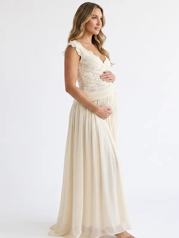 Pregnant model wearing an ivory lace chiffon maternity maxi dress with floral lace bodice, flutter sleeves and flowing skirt for boho baby shower, maternity photoshoot and bridal celebration.