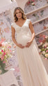 An ivory lace chiffon maternity maxi dress with floral lace bodice, flutter sleeves and flowing skirt for boho baby shower, maternity photoshoot and bridal celebration.