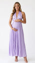 Pregnant model wearing a lavender pleated satin halter maternity maxi dress with deep V neckline and flowing skirt for spring baby shower, garden party and maternity photoshoot.