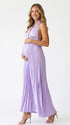 Pregnant model wearing a lavender pleated satin halter maternity maxi dress with deep V neckline and flowing skirt for spring baby shower, garden party and maternity photoshoot.