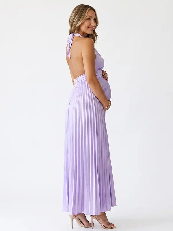 Pregnant model wearing a lavender pleated satin halter maternity maxi dress with deep V neckline and flowing skirt for spring baby shower, garden party and maternity photoshoot.