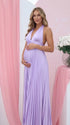 Pregnant model wearing a lavender pleated satin halter maternity maxi dress with deep V neckline and flowing skirt for spring baby shower, garden party and maternity photoshoot.