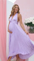 Pregnant model wearing a lavender pleated satin halter maternity maxi dress with deep V neckline and flowing skirt for spring baby shower, garden party and maternity photoshoot.