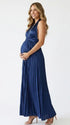 Pregnant model wearing a navy blue pleated satin halter maternity maxi dress with deep V neckline and flowing skirt for wedding guest, maternity photoshoot and formal occasions.