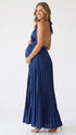 Pregnant model wearing a navy blue pleated satin halter maternity maxi dress with deep V neckline and flowing skirt for wedding guest, maternity photoshoot and formal occasions.