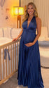 Pregnant model wearing a navy blue pleated satin halter maternity maxi dress with deep V neckline and flowing skirt for wedding guest, maternity photoshoot and formal occasions.