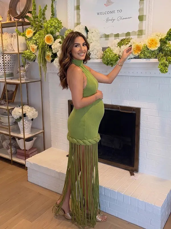 Olive green fringe halter maternity maxi dress with tassel hem, bodycon pregnancy gown for boho baby shower, rustic maternity photoshoot, outdoor pregnancy photography, and nature-inspired maternity portraits.