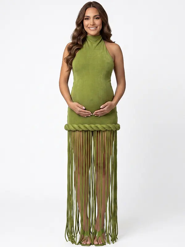 Olive green fringe halter maternity maxi dress with tassel hem, bodycon pregnancy gown for boho baby shower, rustic maternity photoshoot, outdoor pregnancy photography, and nature-inspired maternity portraits.