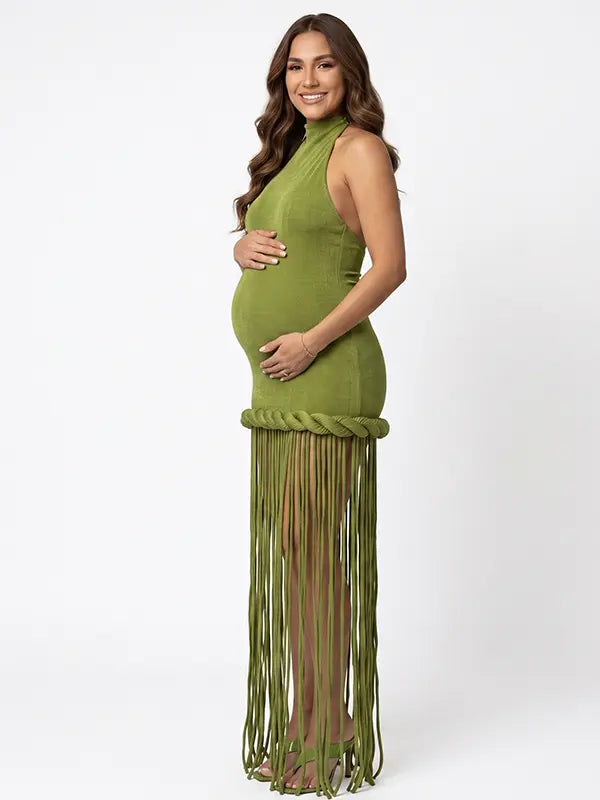 Olive green fringe halter maternity maxi dress with tassel hem, bodycon pregnancy gown for boho baby shower, rustic maternity photoshoot, outdoor pregnancy photography, and nature-inspired maternity portraits.