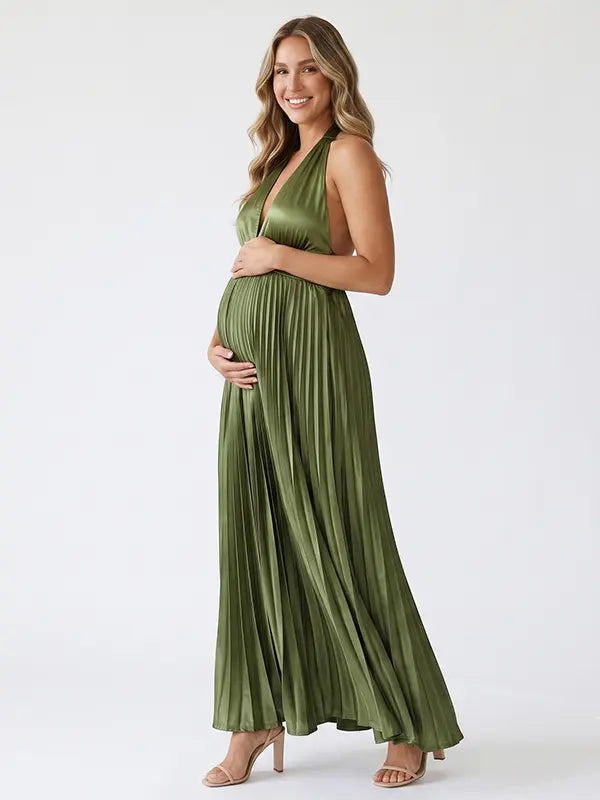 Pregnant model wearing an olive green pleated satin halter maternity maxi dress with deep V neckline and flowing skirt for boho baby shower, rustic maternity photoshoot and outdoor pregnancy celebration.