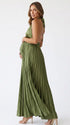 Pregnant model wearing an olive green pleated satin halter maternity maxi dress with deep V neckline and flowing skirt for boho baby shower, rustic maternity photoshoot and outdoor pregnancy celebration.