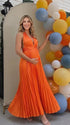Pregnant model wearing an orange pleated satin halter maternity maxi dress with deep V neckline and flowing skirt for fall baby shower, pumpkin patch photos and maternity photography.