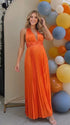 Pregnant model wearing an orange pleated satin halter maternity maxi dress with deep V neckline and flowing skirt for fall baby shower, pumpkin patch photos and maternity photography.