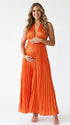 Pregnant model wearing an orange pleated satin halter maternity maxi dress with deep V neckline and flowing skirt for fall baby shower, pumpkin patch photos and maternity photography.