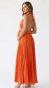 Pregnant model wearing an orange pleated satin halter maternity maxi dress with deep V neckline and flowing skirt for fall baby shower, pumpkin patch photos and maternity photography.