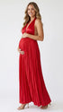Pregnant model wearing a red pleated satin halter maternity maxi dress with deep V neckline, empire waist and flowing skirt for baby shower, gender reveal and maternity photoshoot.