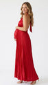 Pregnant model wearing a red pleated satin halter maternity maxi dress with deep V neckline, empire waist and flowing skirt for baby shower, gender reveal and maternity photoshoot.