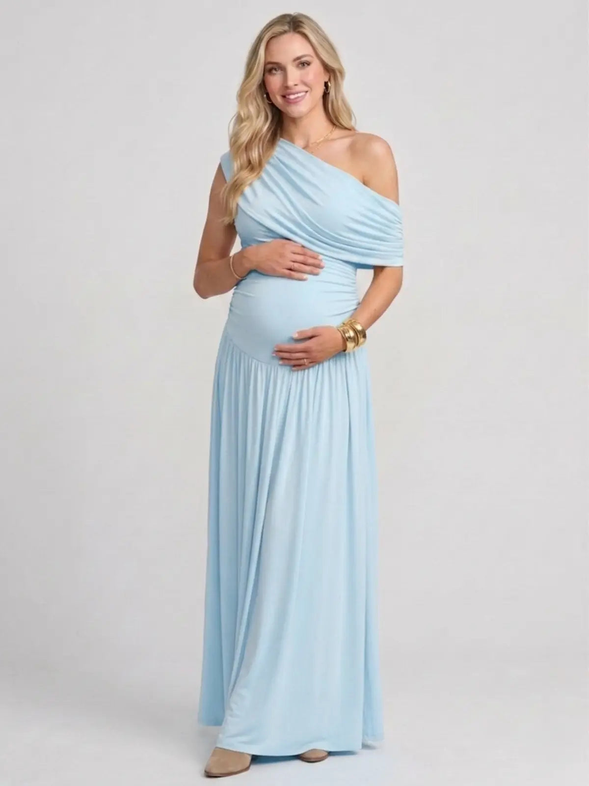 Pregnant woman in a sky blue off-the-shoulder poly-spandex maternity maxi dress with ruched detailing.