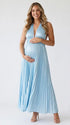 Pregnant model wearing a sky blue pleated satin halter maternity maxi dress with deep V neckline and flowing skirt for beach maternity photoshoot, coastal baby shower and destination pregnancy photography.