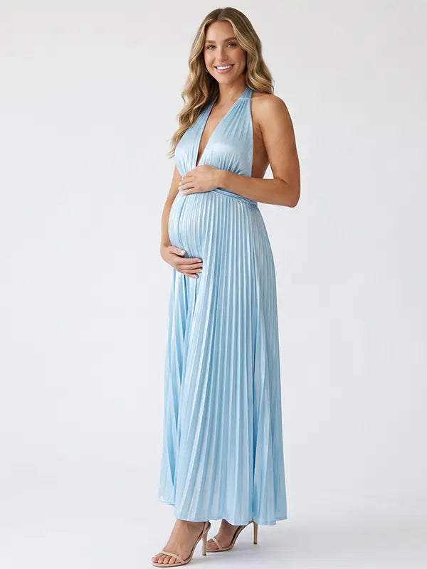Pregnant model wearing a sky blue pleated satin halter maternity maxi dress with deep V neckline and flowing skirt for beach maternity photoshoot, coastal baby shower and destination pregnancy photography.
