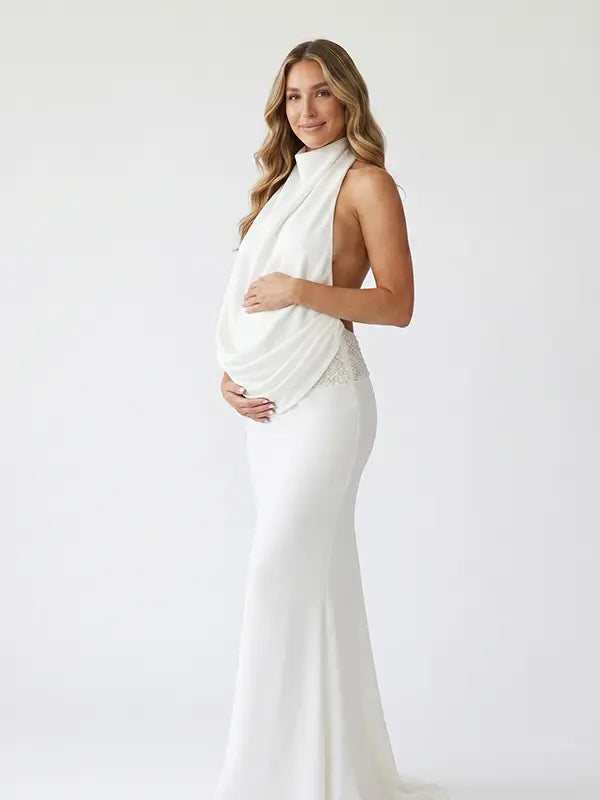white halter maternity gown with open back design and pearl waist detail