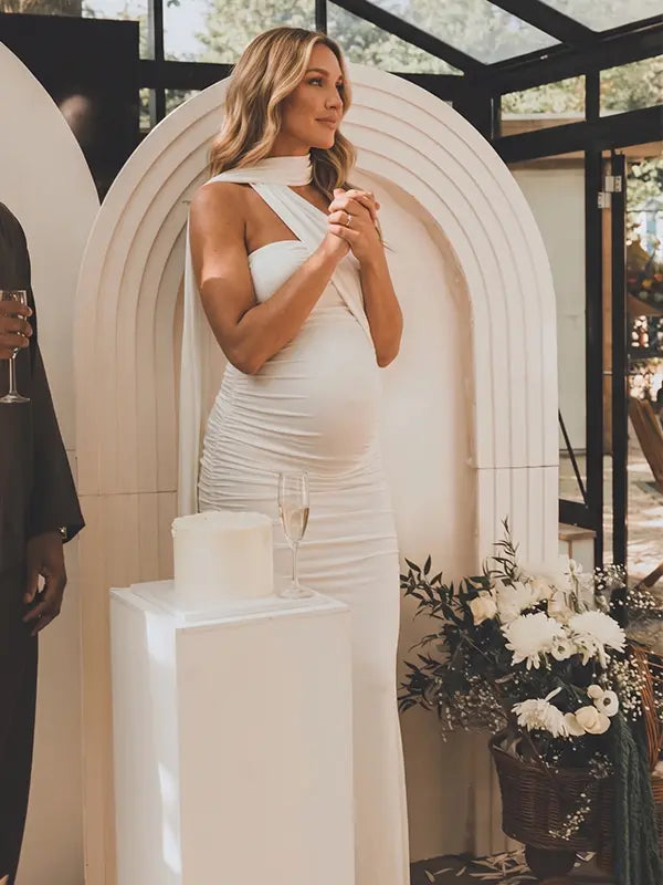 white halter maternity maxi dress with ruched bodycon silhouette and cross neck detail