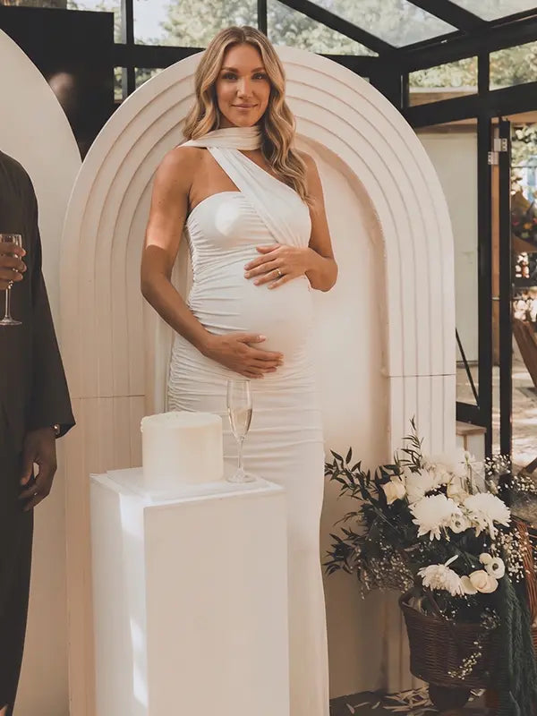 white halter maternity maxi dress with ruched bodycon silhouette and cross neck detail