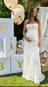 Pregnant woman wearing white floral open back maternity maxi dress for baby shower photoshoot