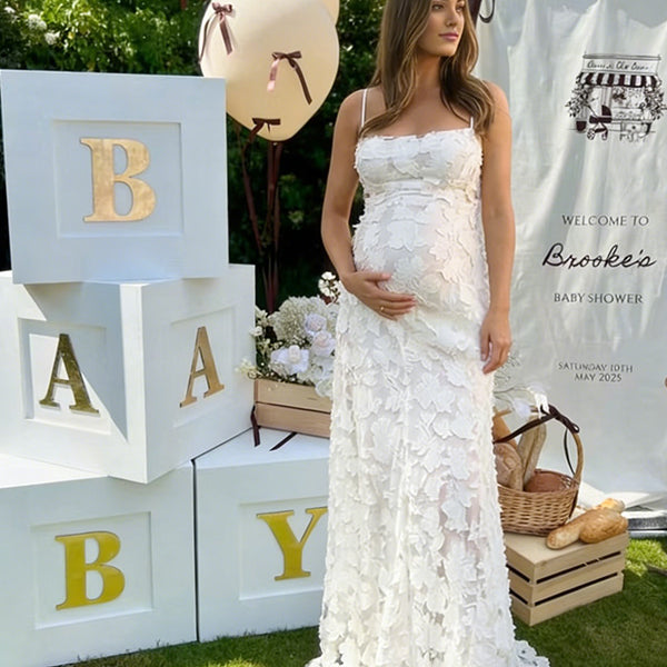 Pregnant woman wearing white floral open back maternity maxi dress for baby shower photoshoot