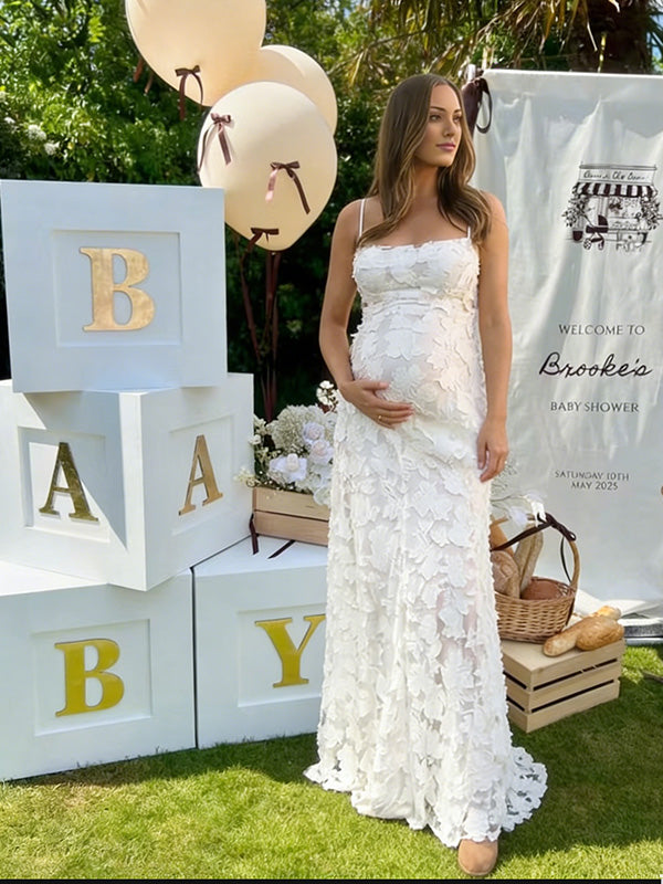 Pregnant woman wearing white floral open back maternity maxi dress for baby shower photoshoot