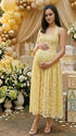 Pregnant woman wearing yellow lace halter maternity maxi dress at baby shower garden party