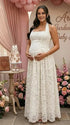 Pregnant woman wearing white lace halter maternity maxi dress at baby shower garden party