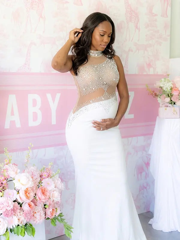 A white rhinestone illusion mesh maternity mermaid maxi dress for luxury maternity photoshoot, baby shower, editorial portrait, and pregnancy announcement.